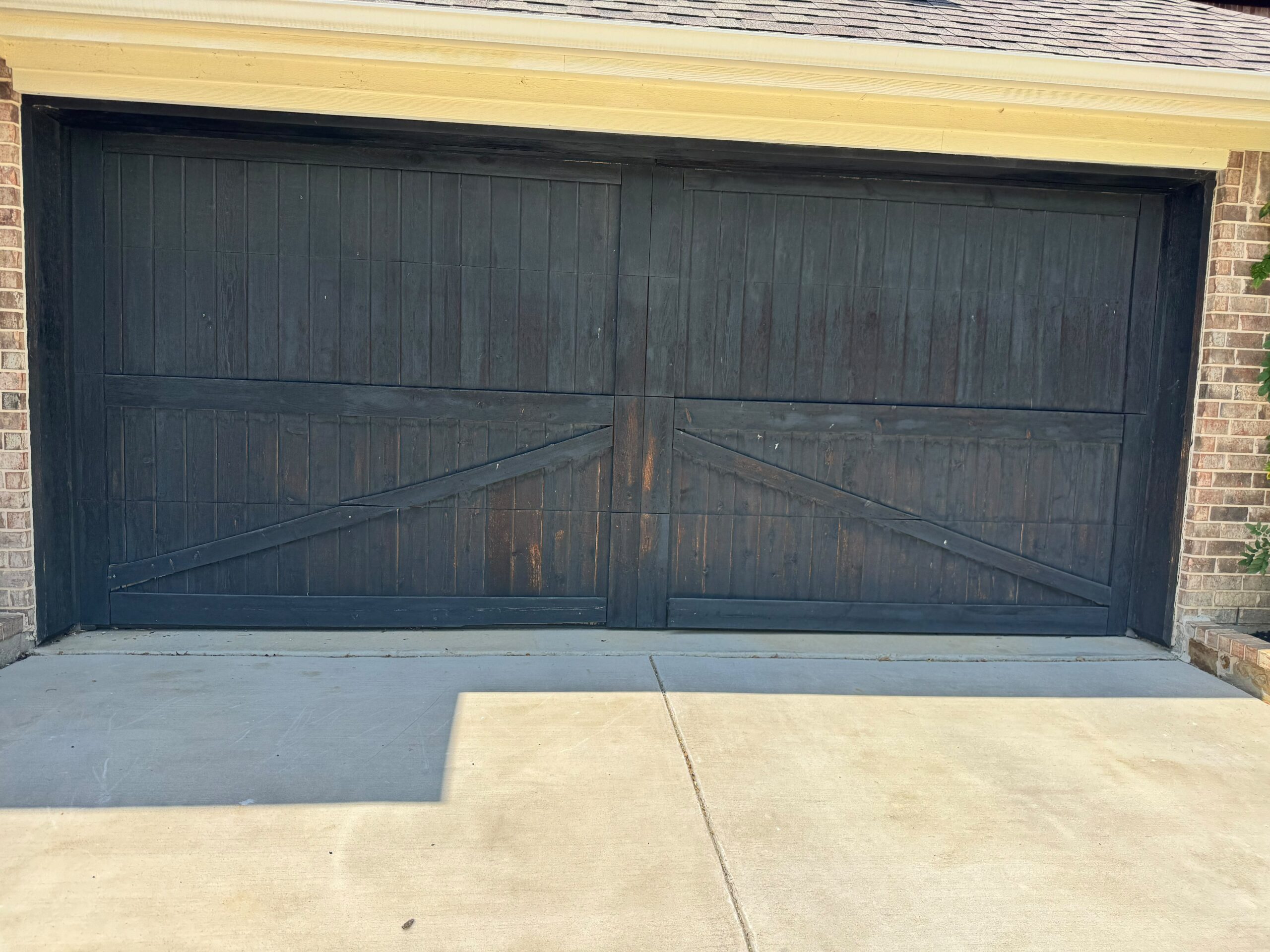 Freshly stained dark wood garage door on a Texas home painted by Beyond Painters