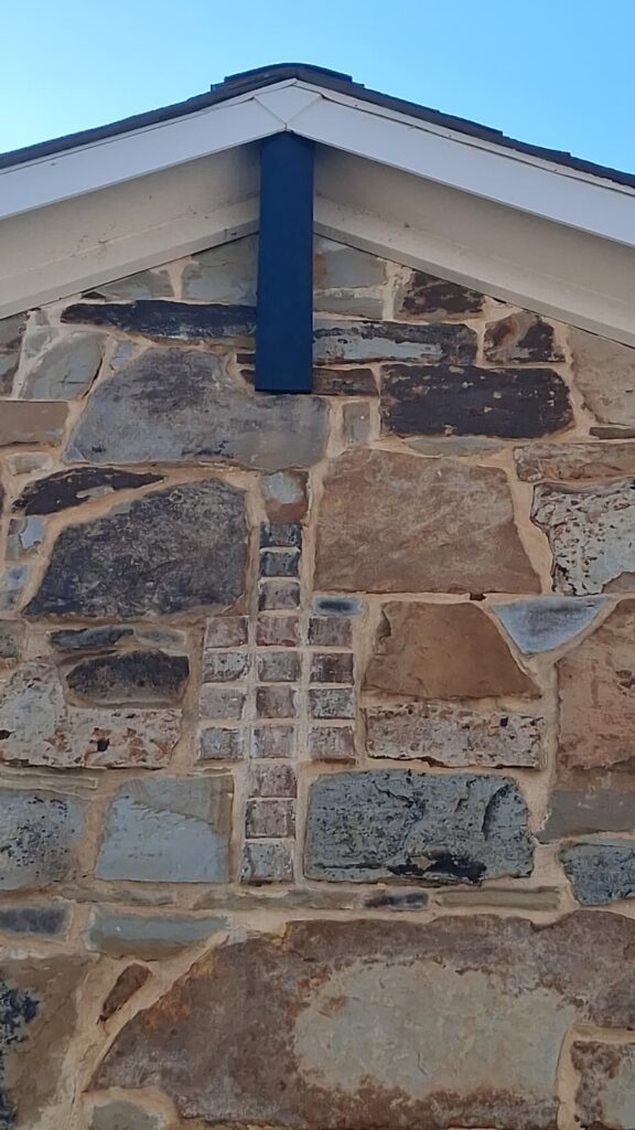 Dark stained wood trim accent on a natural stone gable painted by Beyond Painters